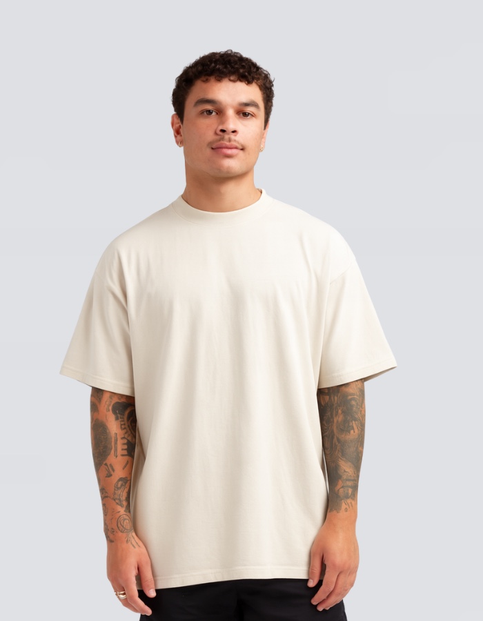 A man in the Heavy Luxe tee in bone, front view on a plain grey ground