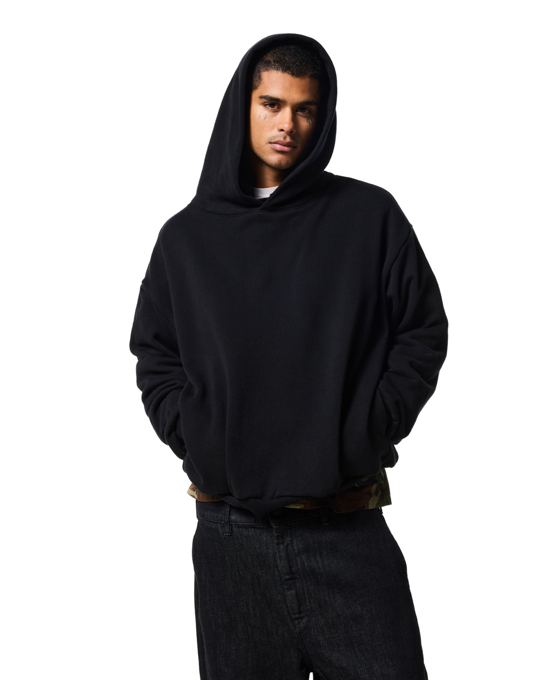 A man in the Hidden side pocket hoodie in jet black, hood up and hands in the side pockets, against white