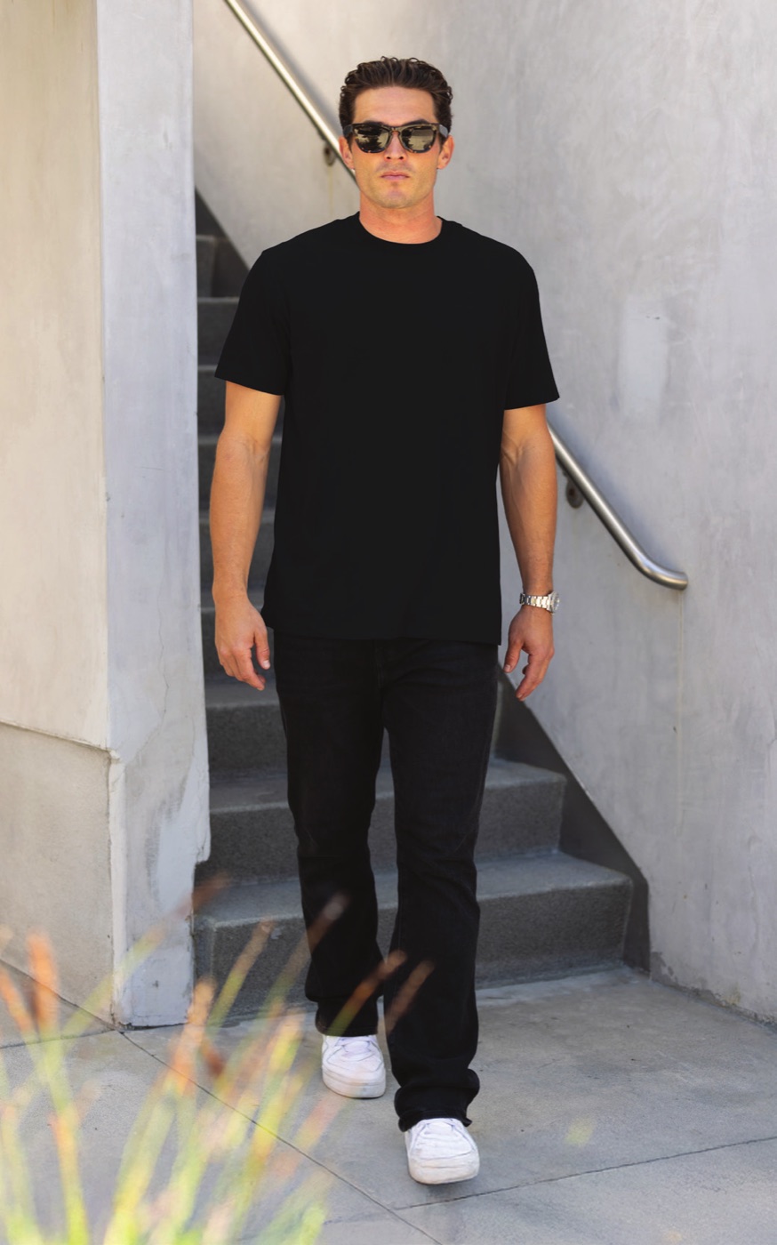 A man walking down concrete steps in the black IND50TEE heavyweight tee